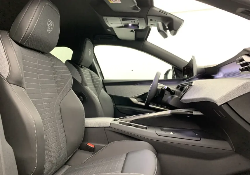 Vue intérieure côté conducteur du Peugeot 3008 Hybrid 145 GT avec sièges tissu et cuir noir, planche de bord moderne et écran panoramique.