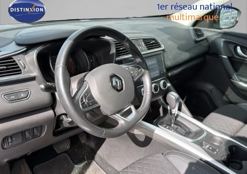 Vue intérieure du poste de conduite du Renault Kadjar gris Highland, avec volant multifonction et console centrale à boîte automatique.