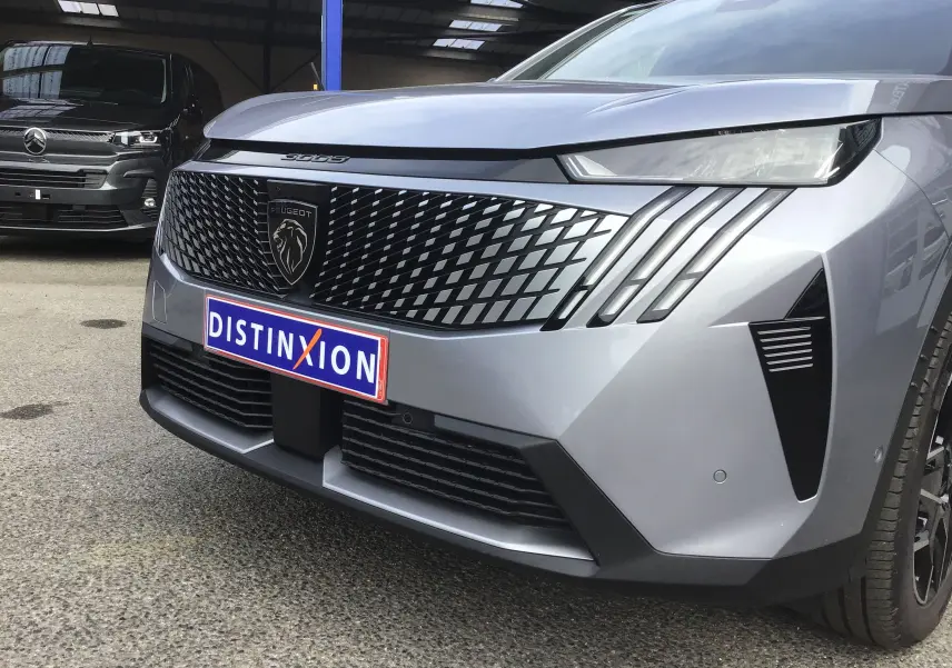 Vue avant droite du Peugeot 3008 1.2 Hybrid gris Artense avec calandre noire à motif losange et phares effilés.