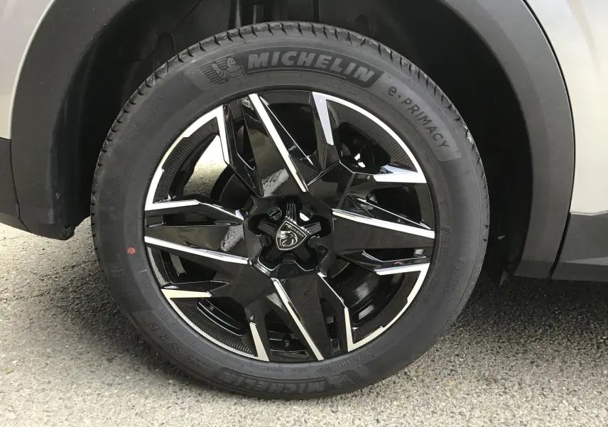 Gros plan sur la roue avant droite du Peugeot 3008 gris Artense, jante alliage noire et argentée de 19 pouces.
