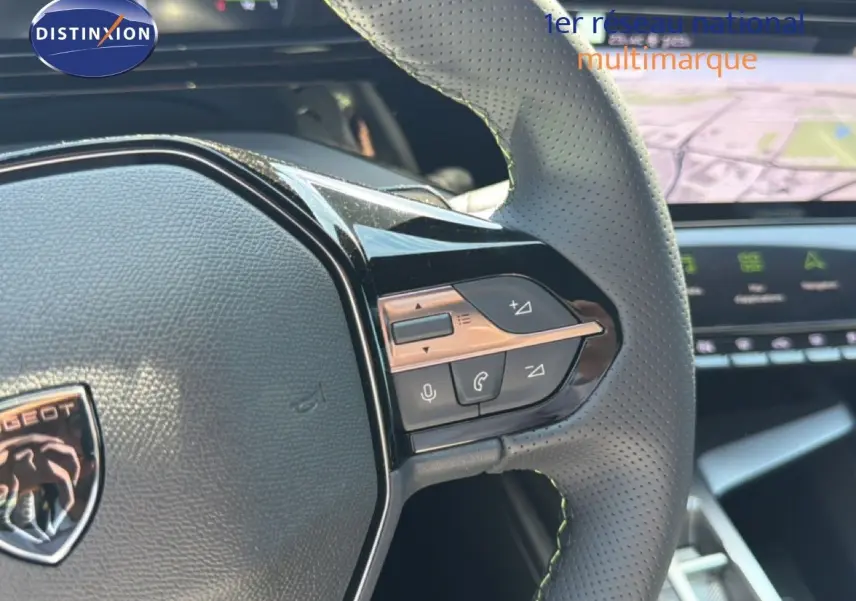 Gros plan sur le volant perforé de la Peugeot 308 Hybrid 145ch GT 2026 avec commandes intégrées et logo lion central.