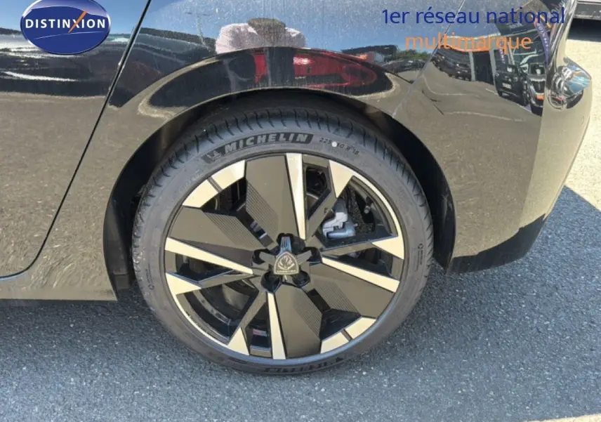 Gros plan sur la roue arrière droite d’une Peugeot 308 Hybrid 145ch GT noir perle métal avec jante design bicolore.