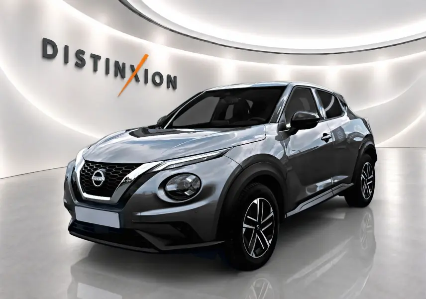 Nissan Juke gris 3/4 avant droit en showroom avec jantes alu et calandre chromée distinctive.