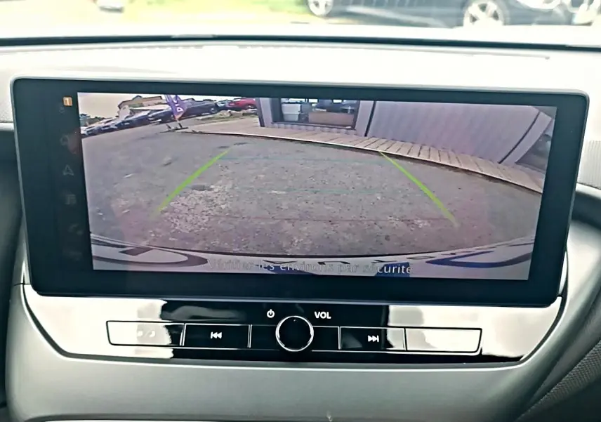 Écran tactile intérieur montrant la caméra de recul d'un Nissan Juke gris, vue frontale du tableau de bord.