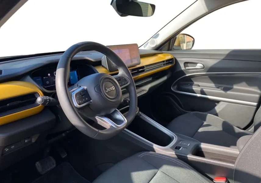 Intérieur du Jeep Avenger électrique 2023, vue côté conducteur, tableau de bord noir et jaune avec écran tactile central.