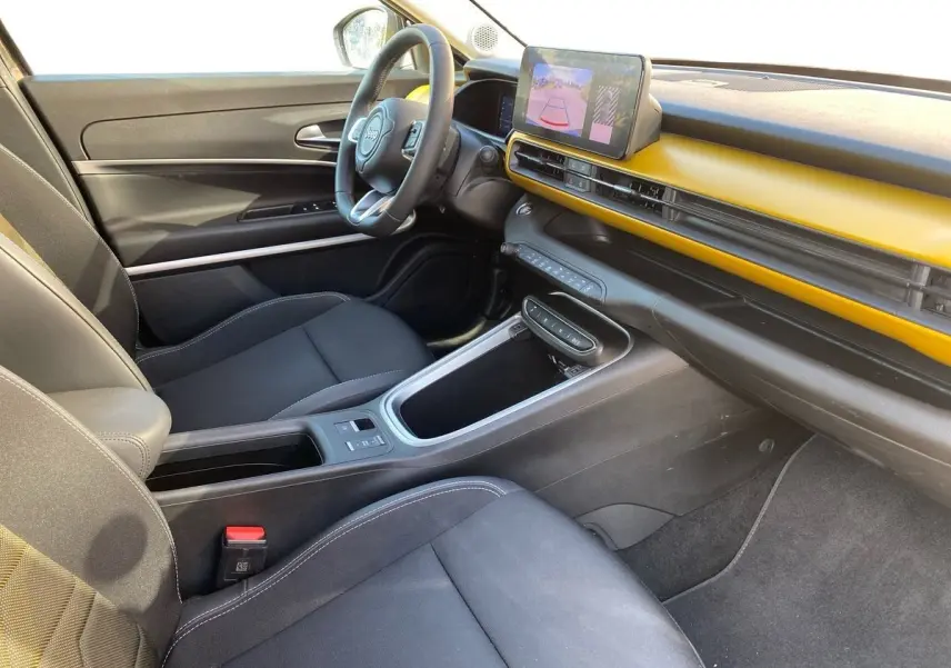 Vue intérieure côté conducteur du Jeep Avenger électrique 2023, tableau de bord noir et jaune avec écran tactile central.