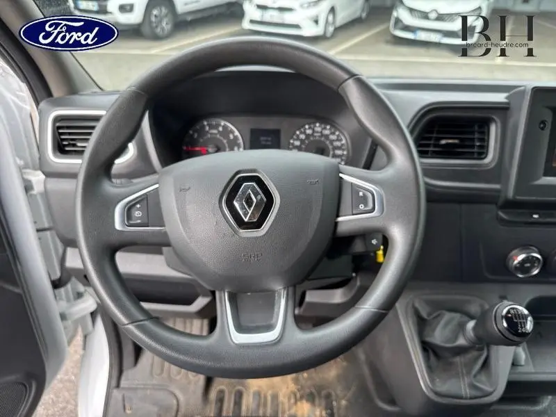 Vue intérieure centrée sur le volant Renault d'un Master blanc, avec tableau de bord et levier de vitesse manuel visibles.