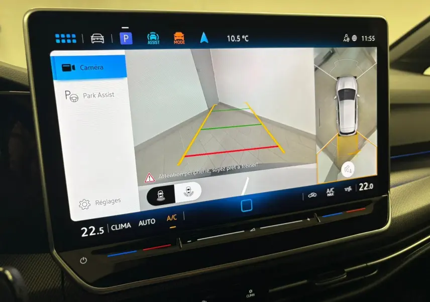 Écran tactile intérieur de la Volkswagen Golf 2025 affichant la caméra 360° en vue arrière avec lignes de guidage colorées.