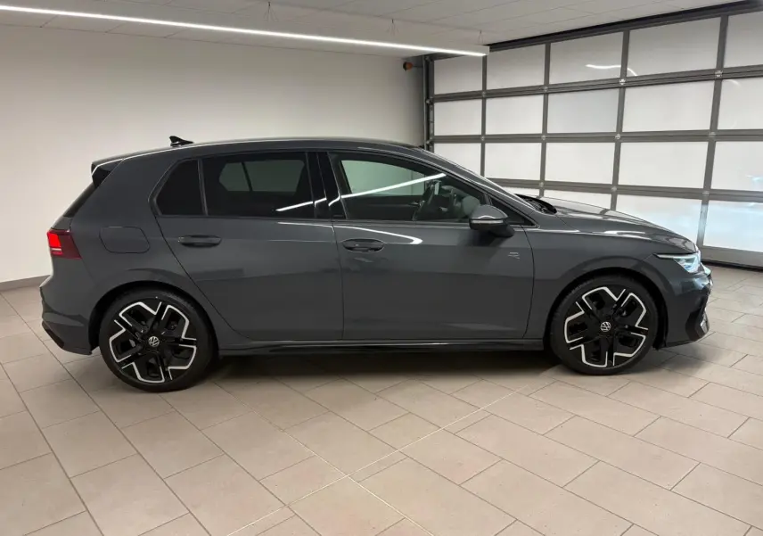 Profil droit d'une Volkswagen Golf 1.5 eTSI 150 DSG7 R-Line Edition gris dauphin, avec jantes noires et détails sportifs.