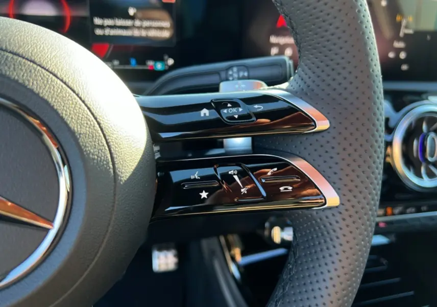 Gros plan sur le volant cuir perforé de la Mercedes Classe A 200D BVA Exclusive Design avec commandes multifonctions.
