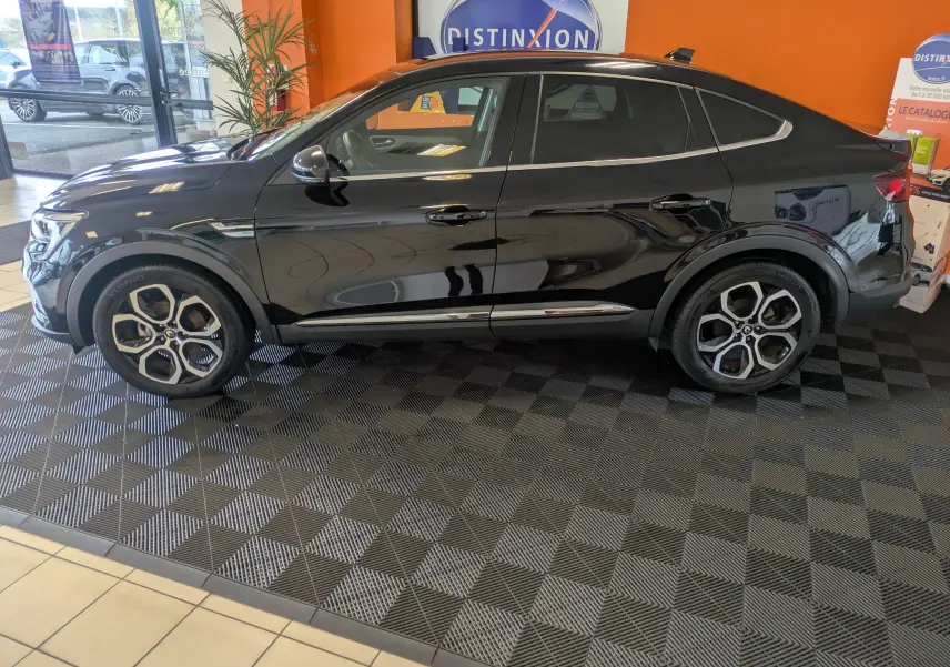 Vue de profil côté gauche d’un Renault Arkana noir 2023, avec jantes bi-ton distinctives et lignes fluides du SUV coupé.