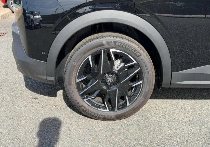 Gros plan sur la roue arrière gauche noire Perla Nera du Peugeot 3008 avec jante alu noire et détails chromés.