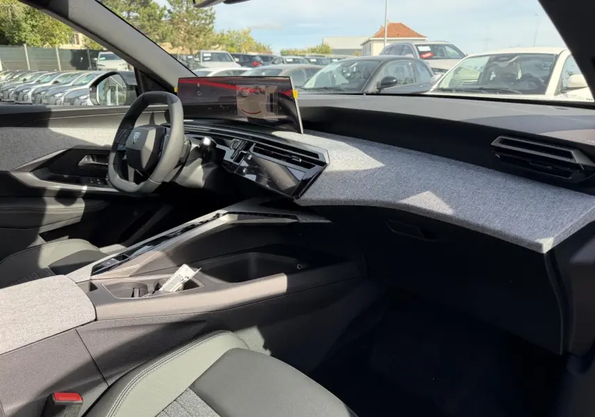 Vue intérieure côté passager du Peugeot 3008 2026, tableau de bord avec habillage tissu gris clair et écran tactile flottant.
