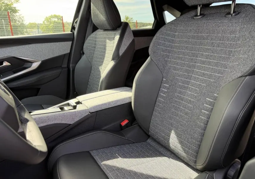 Vue intérieure rapprochée des sièges avant gris tissu et cuir noir du Peugeot 3008 Hybrid 2026, côté conducteur et passager.