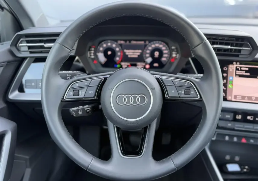 Volant cuir multifonctions de l'Audi A3 Sportback 2024 avec tableau de bord numérique et écran tactile latéral.