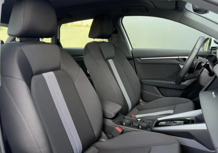 Vue intérieure côté droit de l'Audi A3 Sportback 2024 avec sièges tissu Konsens gris foncé et console centrale moderne.