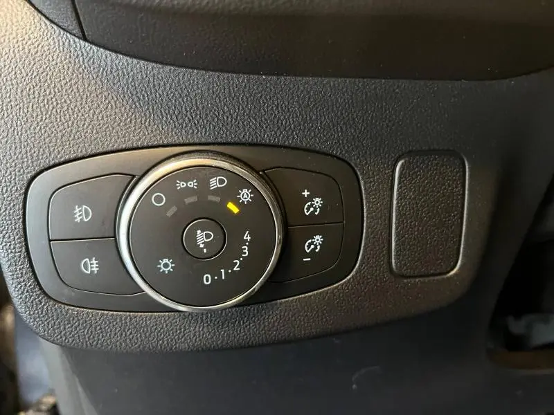 Gros plan sur le bouton de réglage des phares du Ford Puma 2022 en finition Titanium Business, intérieur noir texturé.