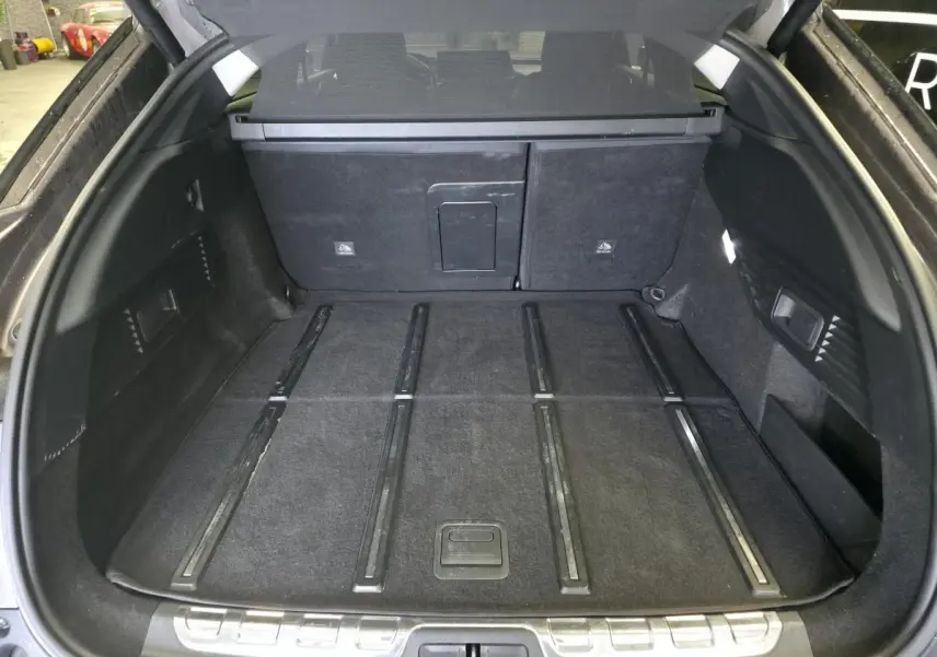 Coffre spacieux ouvert du Citroën C5 X Hybrid gris, avec plancher plat et garniture noire intérieure.