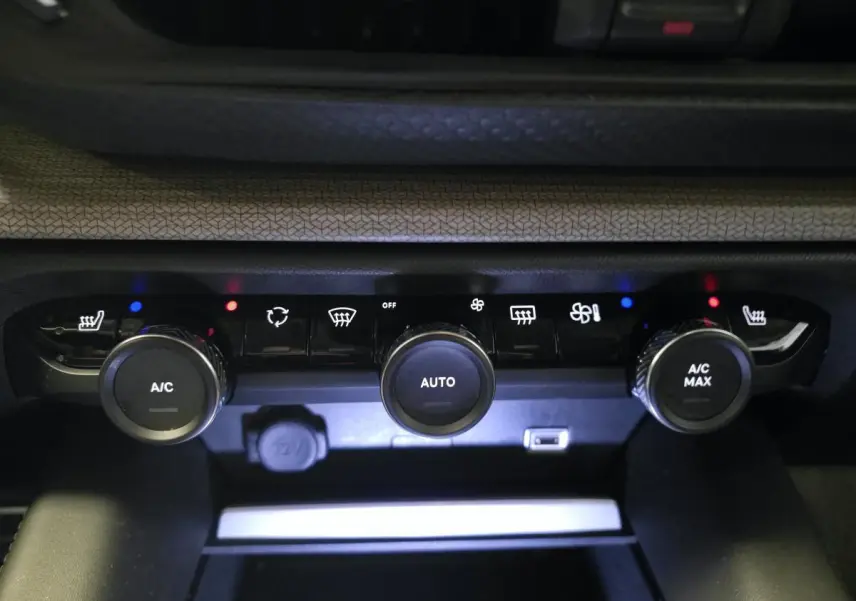 Gros plan sur la console centrale du système de climatisation de la Citroën C5 X hybride rechargeable gris, avec commandes rotatives et voyants lumineux.