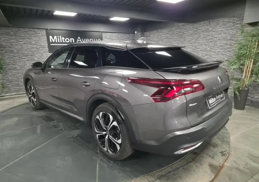 Vue 3/4 arrière droite d'une Citroën C5 X hybride rechargeable gris métallisé avec jantes alliage et vitres teintées.