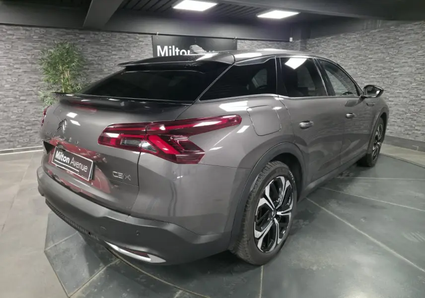 Vue 3/4 arrière droit d'une Citroën C5 X hybride rechargeable gris métallisé avec jantes alliage noires et vitres teintées.