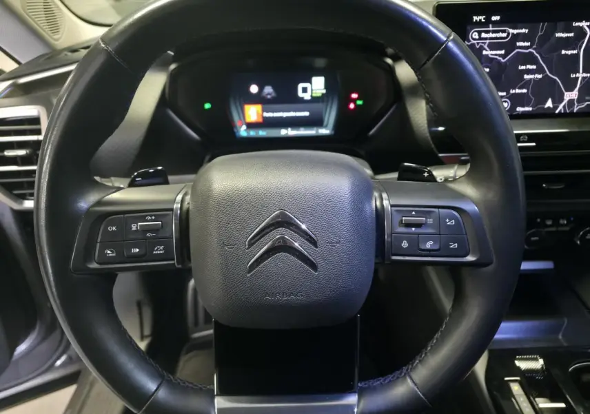 Volant cuir noir de Citroën C5 X Hybrid 2023 avec commandes intégrées et tableau de bord numérique en arrière-plan.