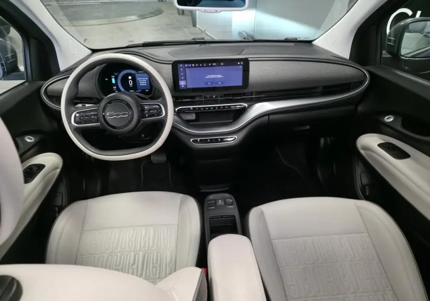 Intérieur avant de la Fiat 500 Cabriolet électrique 2022, tableau de bord moderne et sièges en éco-cuir clair avec volant bicolore.