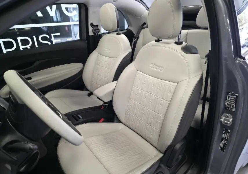 Vue intérieure côté conducteur de la Fiat 500 Cabriolet électrique 2022 avec sellerie éco-cuir beige et volant bicolore.