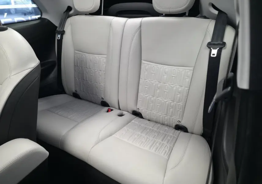 Vue rapprochée de la banquette arrière beige clair avec motifs FIAT embossés dans une Fiat 500 Cabriolet électrique.