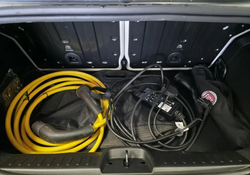 Coffre ouvert d'une FIAT 500 Cabriolet électrique gris foncé, montrant câbles de recharge jaune et noir rangés.