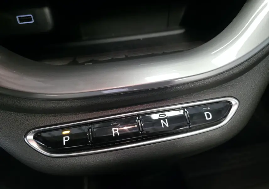 Gros plan sur la commande de boîte automatique noire avec éclairage orange sur la position P dans une Fiat 500 Cabriolet électrique gris foncé.