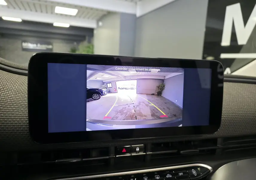 Écran central montrant la caméra de recul d'une Fiat 500 Cabriolet électrique gris foncé dans un garage.