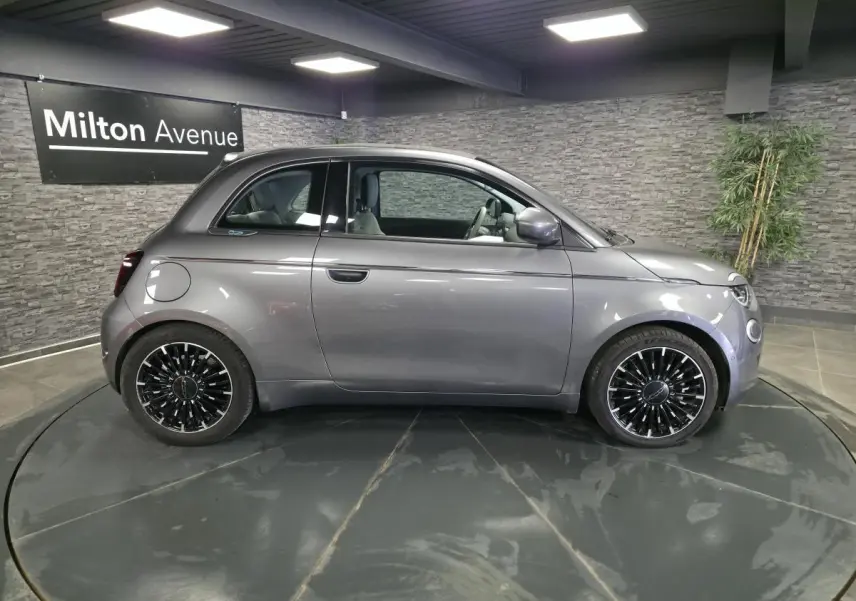 Profil droit de la Fiat 500 Cabriolet électrique 2022 gris foncé avec jantes alliage bicolores en showroom.