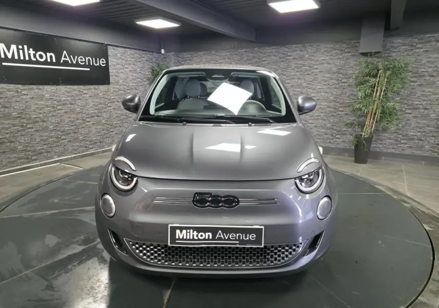 Vue frontale d'une FIAT 500 Cabriolet électrique gris foncé avec logo 500 noir et calandre épurée en intérieur showroom.
