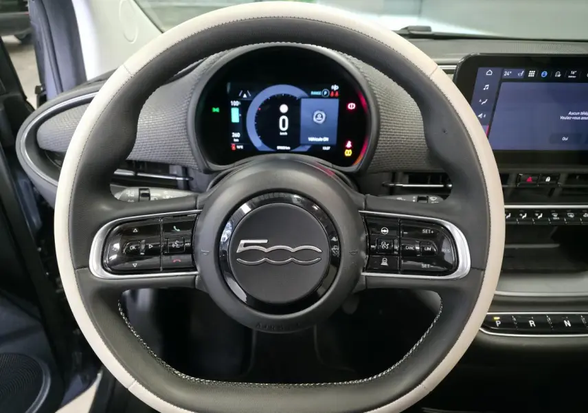 Vue rapprochée du volant bicolore noir et beige avec logo 500, tableau de bord numérique et écran tactile de la Fiat 500 Cabriolet électrique.