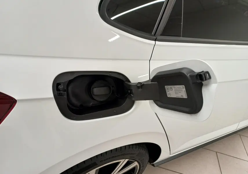 Vue latérale droite du coffre à carburant ouvert sur Volkswagen Polo blanc pur avec vitres arrière surteintées.