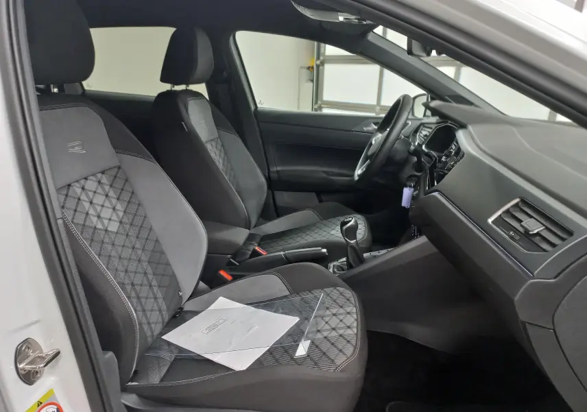 Vue intérieure côté gauche d'une Volkswagen Polo blanche, sièges R-Line avec surpiqûres et volant visible.