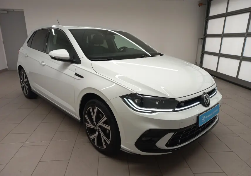 Vue 3/4 avant droit d'une Volkswagen Polo blanc pur avec phares LED et jantes alliage R-Line dans un garage.
