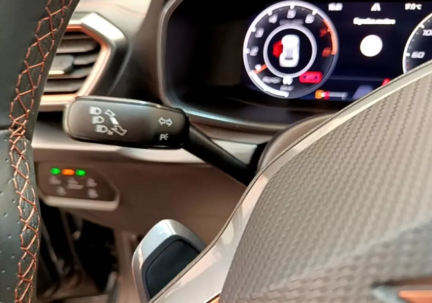 Gros plan sur le volant en cuir avec surpiqûres orange et tableau de bord numérique du CUPRA Formentor gris foncé.