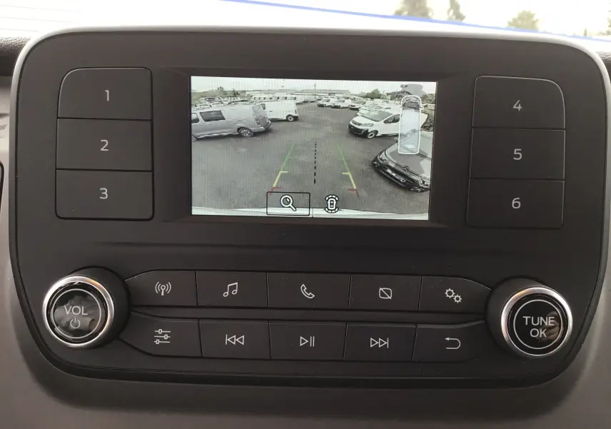 Écran central du Ford Transit Fourgon 2023 montrant la caméra de recul avec vue sur un parking extérieur.