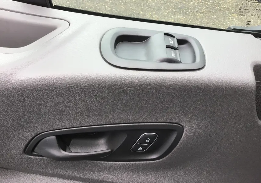 Détail de la porte côté conducteur du Ford Transit Fourgon blanc 2023, montrant les commandes de vitres et de verrouillage.
