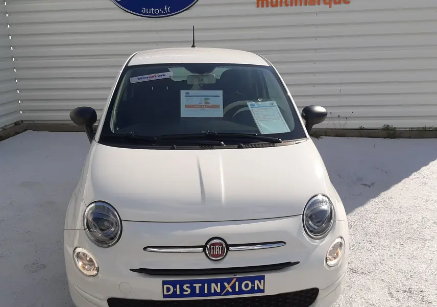 Vue avant d'une Fiat 500 blanche 2023 avec phares ronds et logo FIAT sur calandre chromée.