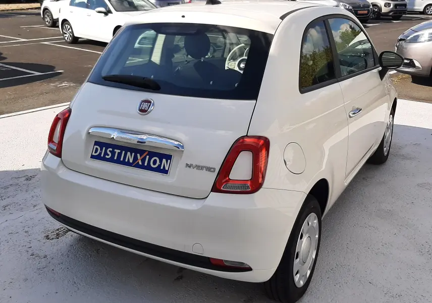 Vue 3/4 arrière droite d'une Fiat 500 blanche hybride 2023 avec feux arrière rectangulaires et logo FIAT visible.