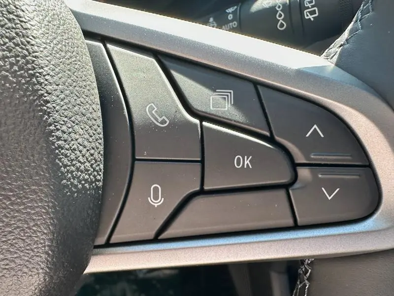 Gros plan sur les commandes multifonctions noires du volant du Dacia Bigster 2025, boutons appel, micro et navigation.