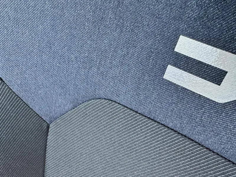 Gros plan sur le tissu bleu et gris du siège avant du Dacia Bigster 2025 avec logo blanc partiel visible