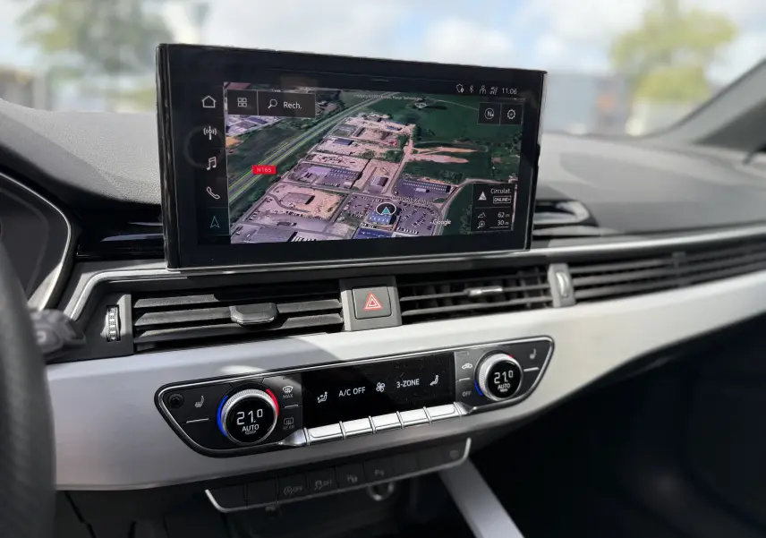 Vue rapprochée du tableau de bord gris clair de l'Audi A4 Avant 2023 avec écran tactile affichant la navigation GPS.