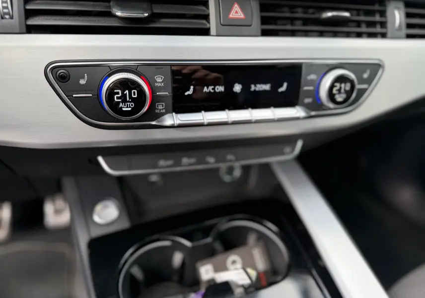 Gros plan sur la console centrale de l'Audi A4 Avant 35 TDI 2023, affichant la climatisation digitale à 21°C.