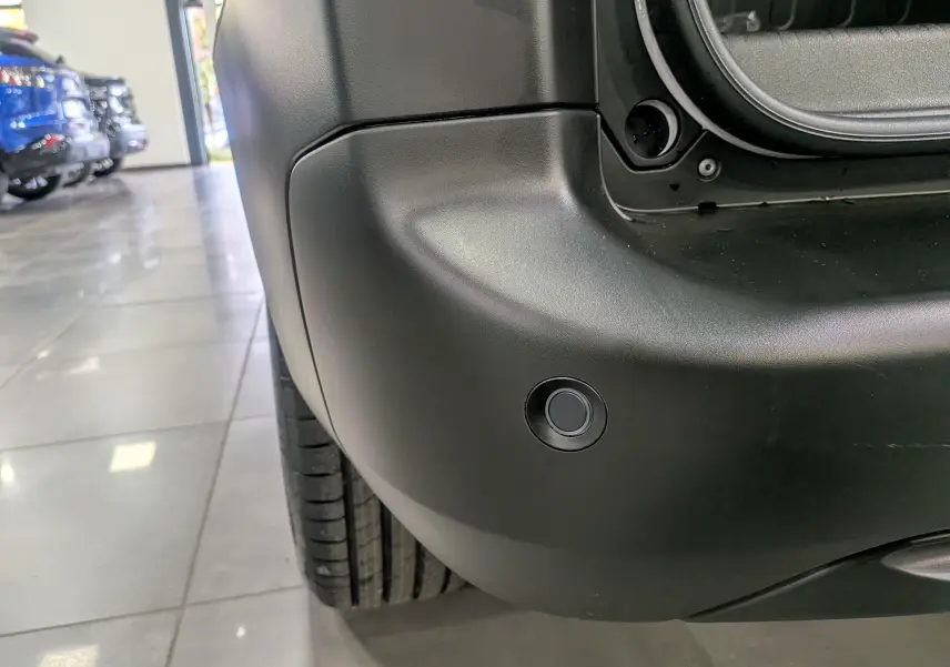 Gros plan sur le pare-chocs arrière noir du Citroën Berlingo blanc glacier 2025, montrant un capteur de stationnement.