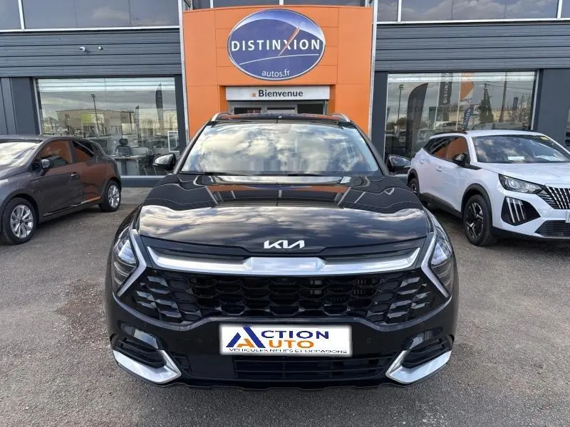 Vue de face d'un Kia Sportage noir Basalte métallisé 2022 avec calandre noire et inserts chromés, stationné devant un concessionnaire.