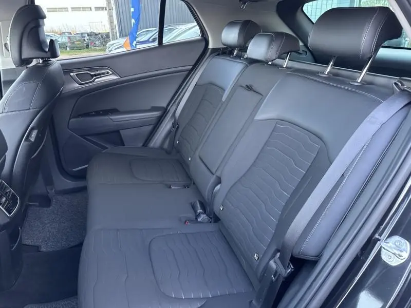 Vue intérieure côté droit des sièges arrière en cuir synthétique noir du Kia Sportage 2022, avec appuie-têtes et ceintures visibles.